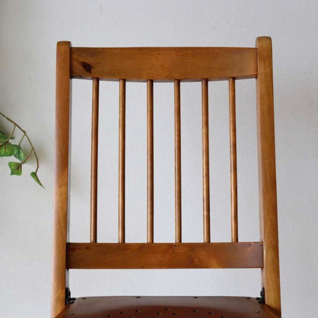 Vintage British mid-century teak folding chair with vertical slat back and smooth wood grain.