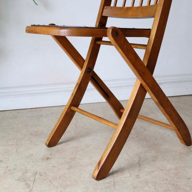 Vintage British mid-century folding teak chair with visible wood grain and sturdy crossed legs.
