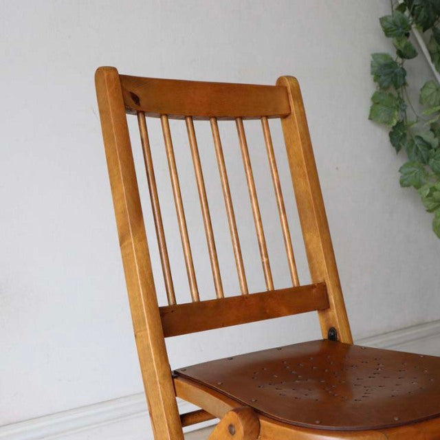 Vintage teak folding chair with slender vertical spindle back, mid-century British design, warm wood grain finish, sturdy.