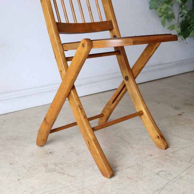 Vintage teak folding chair with slender spindled backrest, mid-century British design, warm wood grain, angled legs with.