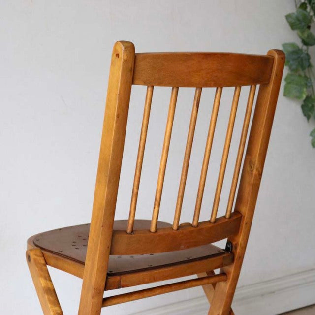 Vintage British teak folding chair with mid-century spindle backrest and smooth wood grain finish.