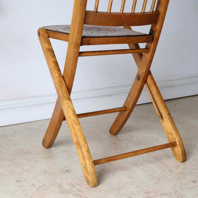 Vintage teak folding chair with visible wood grain, angled legs, and mid-century British design.