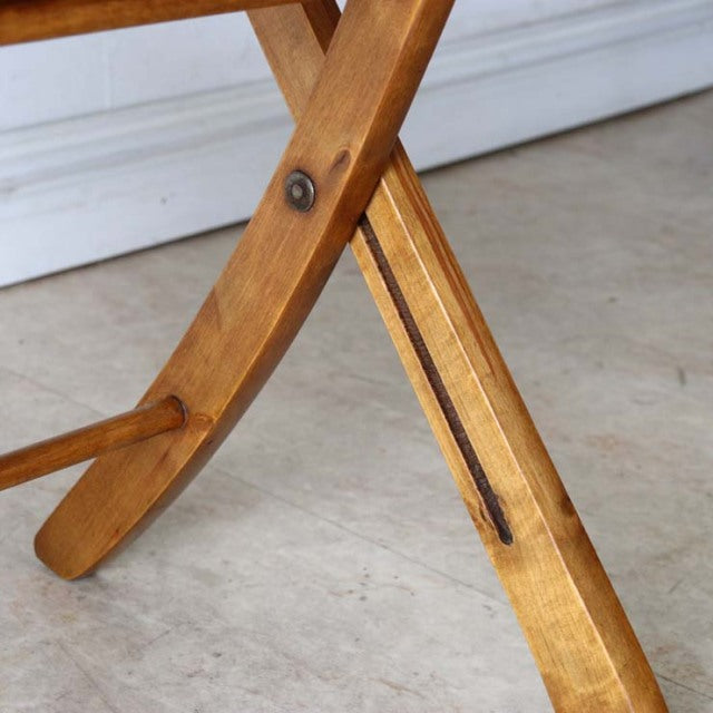 Mid-century British teak folding chair leg with visible wood grain and brass hardware detail.