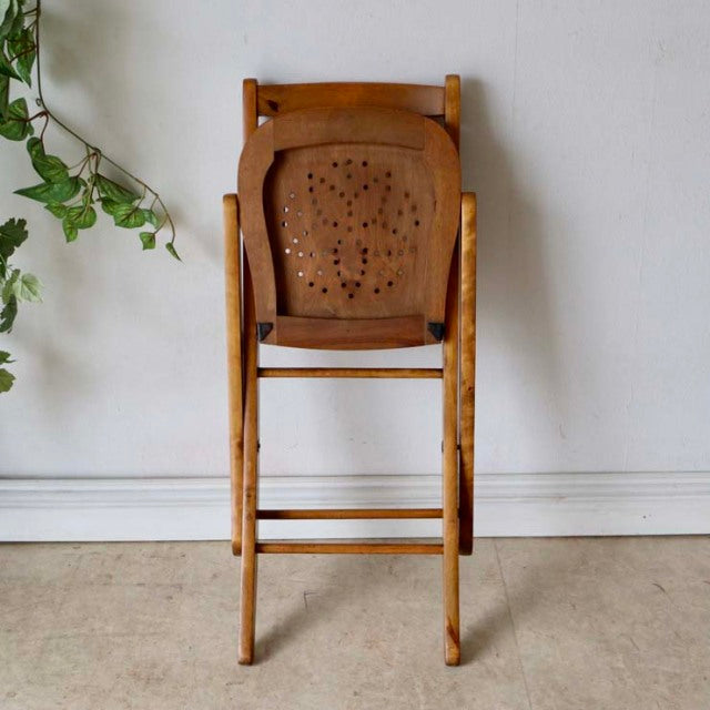 Vintage British mid-century folding chair in teak with perforated backrest and slender legs.
