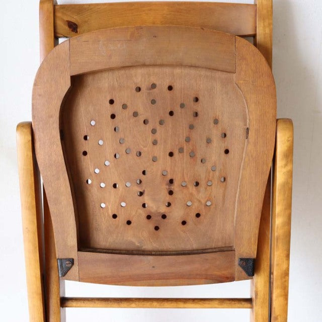 Vintage British teak folding chair with mid-century design, rounded backrest and perforated seat panel.