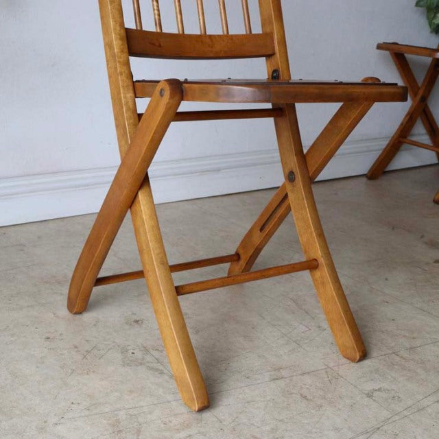 Mid-century British vintage teak folding chair with curved legs and slatted backrest, showing rich wood grain and smooth.