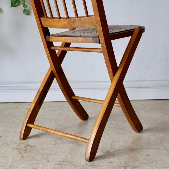 Vintage British mid-century teak folding chair with slatted backrest and curved legs, smooth wood grain visible.