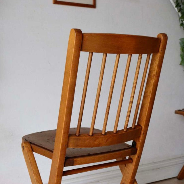 Vintage British teak folding chair with mid-century slender spindle back and warm wood grain finish.