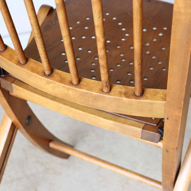 Vintage British mid-century teak folding chair with spindle backrest and visible wood grain detailing.