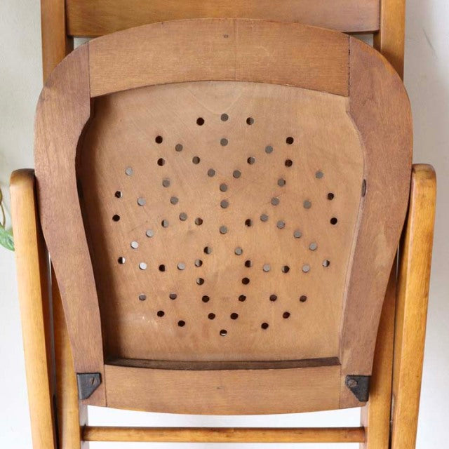 Mid-century vintage British teak folding chair back with perforated geometric pattern and curved wooden frame.
