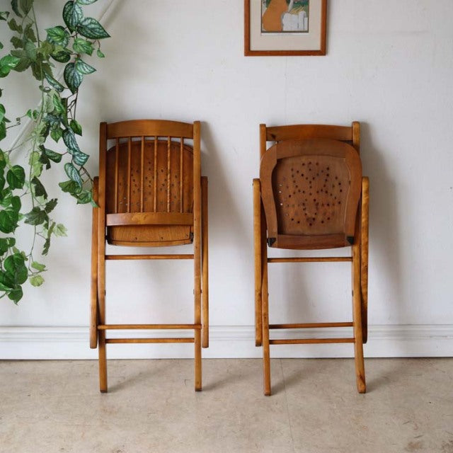 Pair of vintage teak folding chairs with slatted backs and simple mid-century British design, showing warm wood grain and.