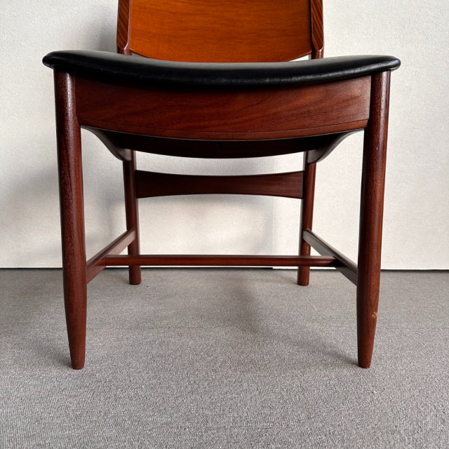 British vintage mid-century dining chair with rich teak wood frame and black leather seat, tapered legs with visible wood.