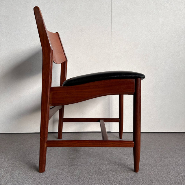 Mid-century British vintage dining chair in polished teak wood with sleek black leather seat and tapered legs.
