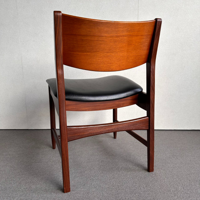 Vintage British mid-century teak dining chair with black leather seat and smooth curved backrest.