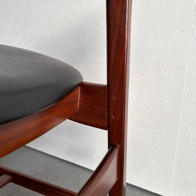 British vintage mid-century teak dining chair with black leather seat and rich wood grain detail.