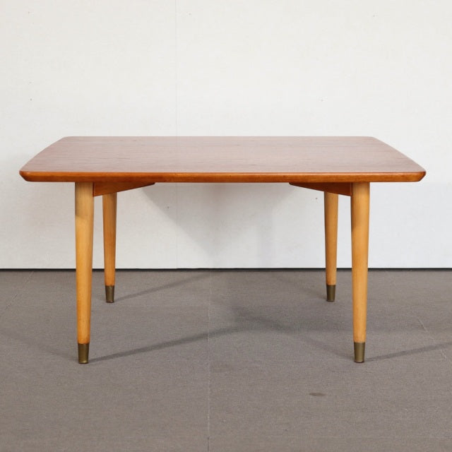 Mid-century vintage teak coffee table with British and Danish design influences, tapered legs with brass caps, smooth wood.