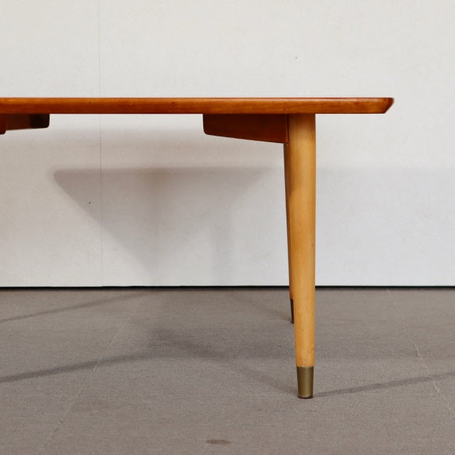 Mid-century vintage teak coffee table with tapered wooden legs and brass-capped feet, showcasing smooth wood grain and clean .