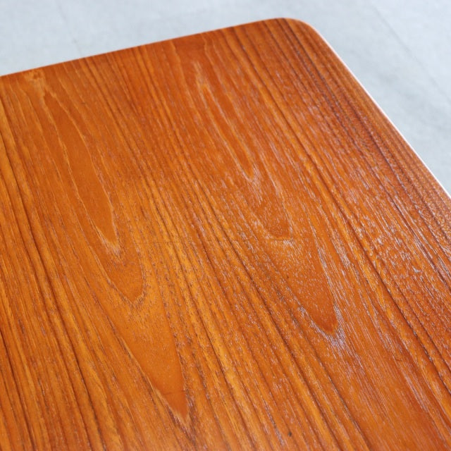 Vintage mid-century teak coffee table top showing rich wood grain and smooth rounded edges, British-Denmark design influence.