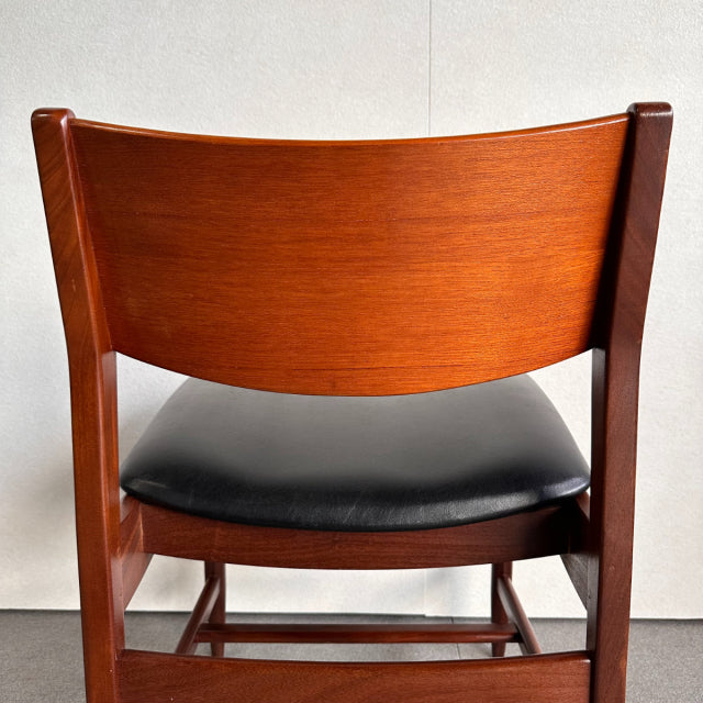 Vintage British mid-century dining chair with rich teak wood frame and black leather seat, showcasing smooth wood grain and.