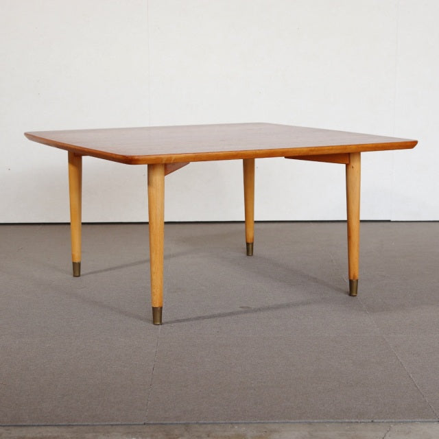 Mid-century vintage teak coffee table with slender tapered legs featuring brass caps, Scandinavian design influences from.