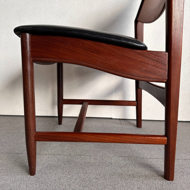 Mid-century British vintage dining chair with rich teak wood frame and smooth black leather seat and backrest.