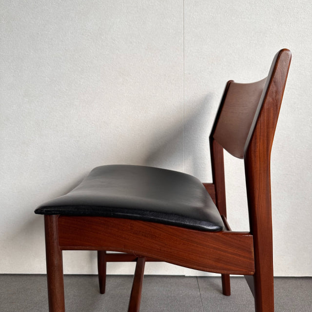 Mid-century British vintage dining chair with teak frame and smooth black leather padded seat and backrest, showcasing rich.