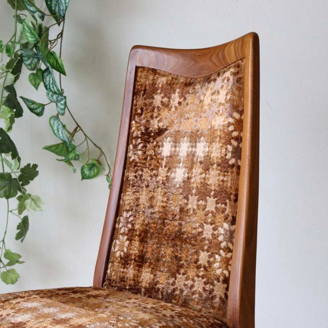 Set of four vintage G-Plan teak dining chairs with curved British mid-century frames and patterned fabric seats, showcasing.