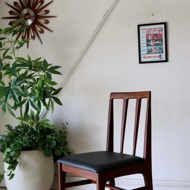 Vintage teak dining chair in British mid-century Danish style, featuring vertical slats and black cushioned seat.