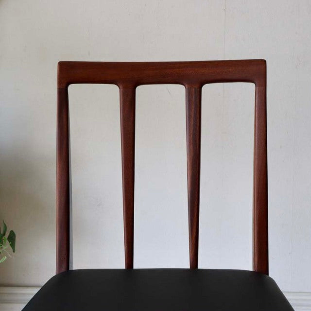 Set of four A.Younger Ltd. British mid-century dining chairs in teak with black upholstered seats and slender tapered legs.