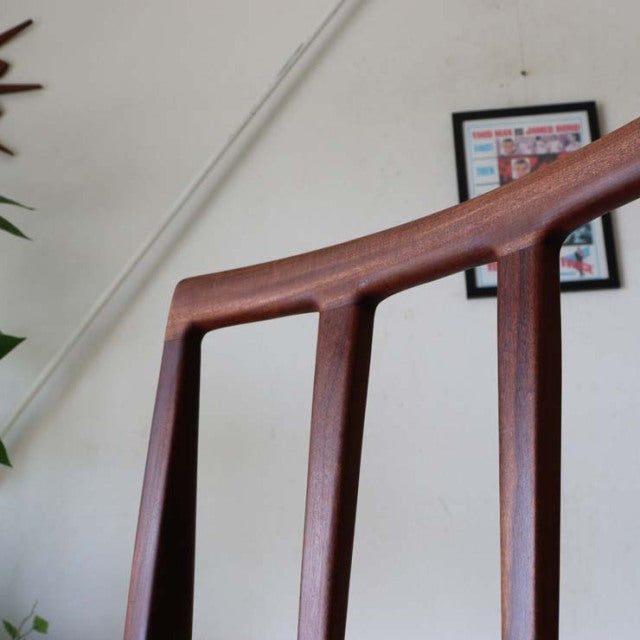 Vintage teak dining chair with sleek mid-century British design, slender vertical slats, and smooth wooden grain finish.