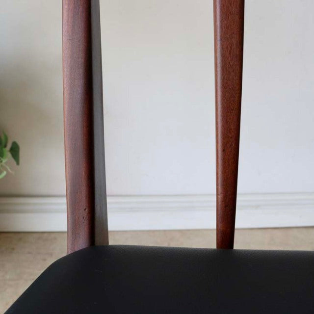 Vintage teak dining chair with slender British mid-century legs and black cushioned seat, Danish design influence visible in .