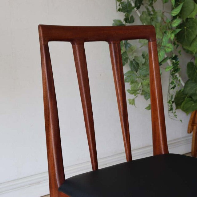 Vintage mid-century British teak dining chair with vertical slats and black cushioned seat, sleek tapered legs.