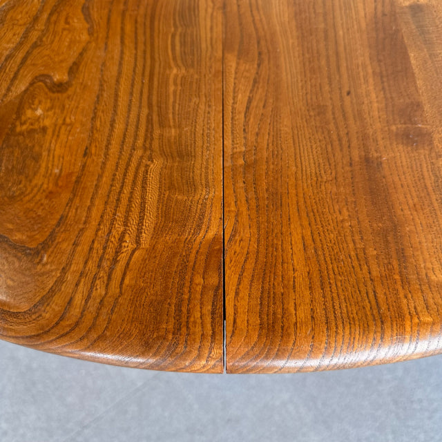 Close-up of vintage British mid-century ERCOL teak dining table top with rich wood grain and rounded edge.