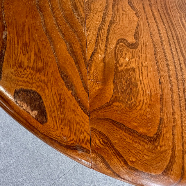 Close-up of vintage British mid-century ERCOL teak dining table top showing rich wood grain and smooth finish.