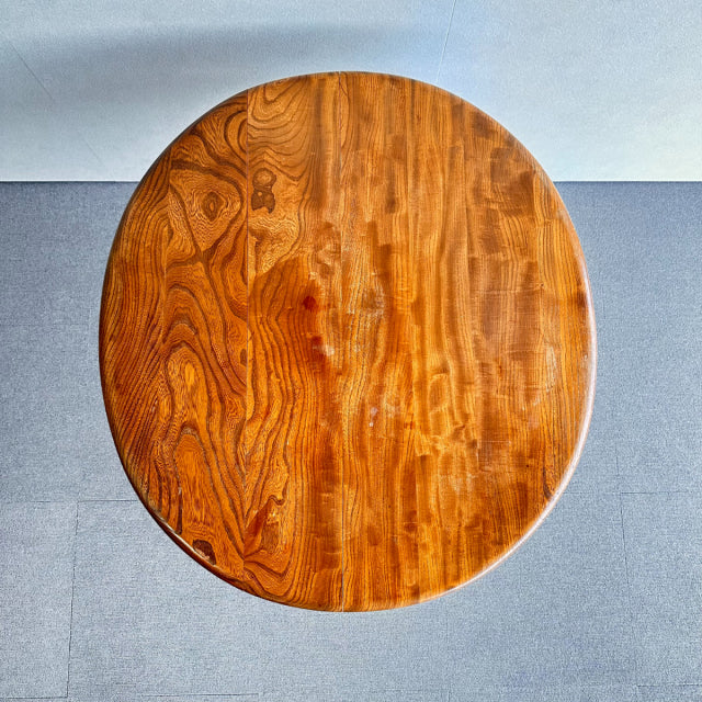 Round vintage teak dining table by Ercol, showcasing rich wood grain and slender mid-century British legs with Danish design .