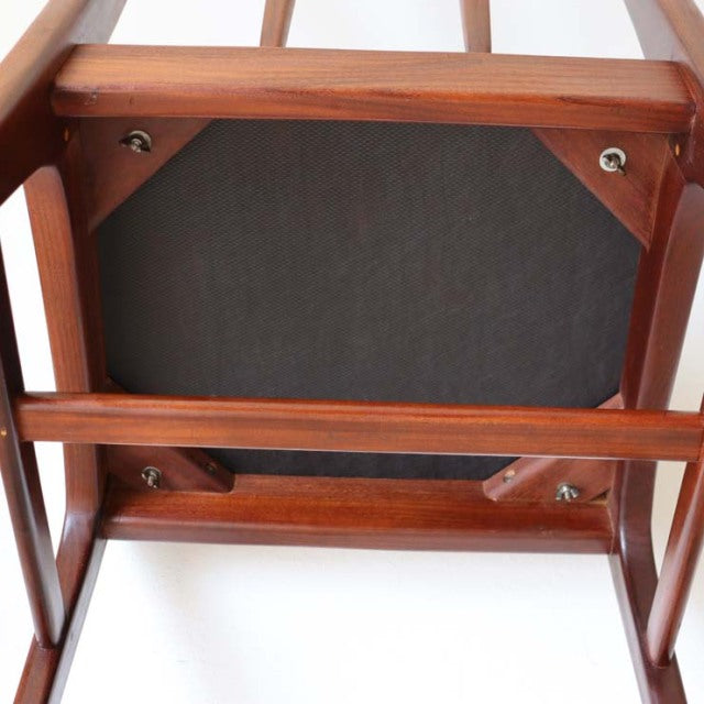 Vintage teak dining chair from British mid-century design, showcasing solid wood grain and sturdy angled legs with visible.