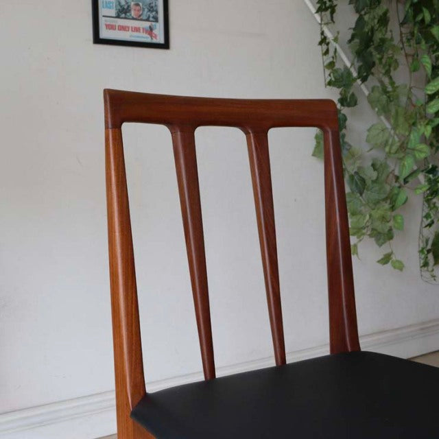 Vintage mid-century teak dining chair with British design, slender vertical slats and black cushioned seat.