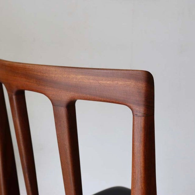 Vintage mid-century teak dining chair with smooth wood grain, British design, slender tapered legs, and minimalist backrest.
