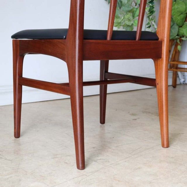 Vintage teak dining chair from mid-century British-Denmark design with sleek tapered legs and black upholstered seat.