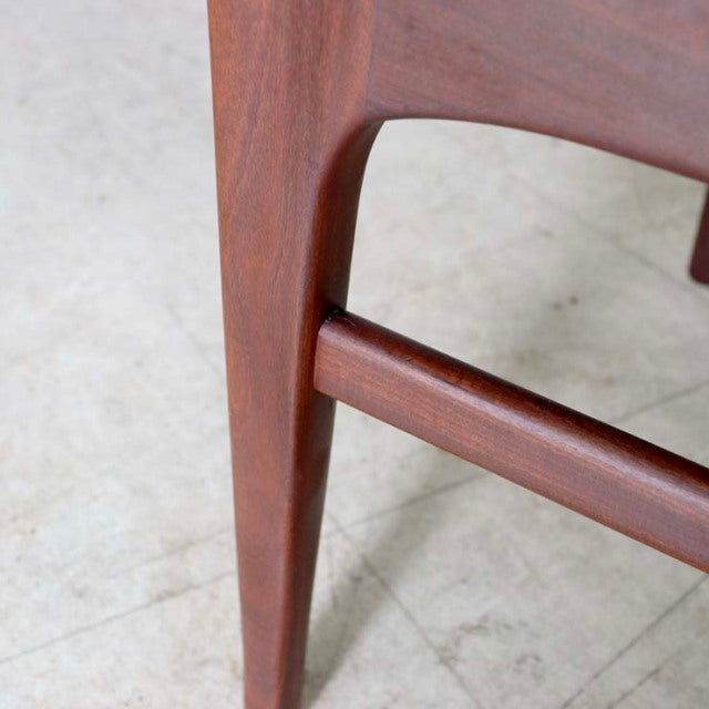 Close-up of vintage teak dining chair leg with smooth wood grain and mid-century British design from Denmark.
