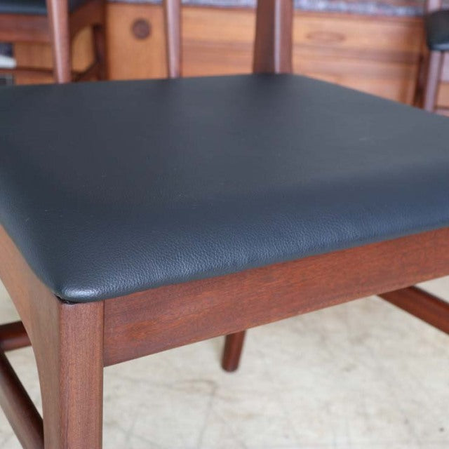 Vintage mid-century teak dining chair with smooth black leather seat, slender tapered legs, and clean British-Denmark design .