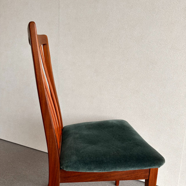 Vintage British G-Plan dining chair with teak frame and dark green velvet seat cushion, mid-century Denmark design, visible.