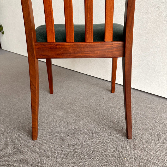 Mid-century British G-Plan dining chair with teak frame, visible wood grain, and dark upholstered seat, angled tapered legs.