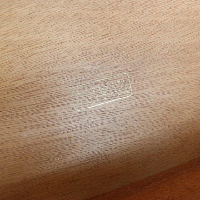 Close-up of vintage teak wood grain with subtle brand stamp from British mid-century Austinsuite sideboard.