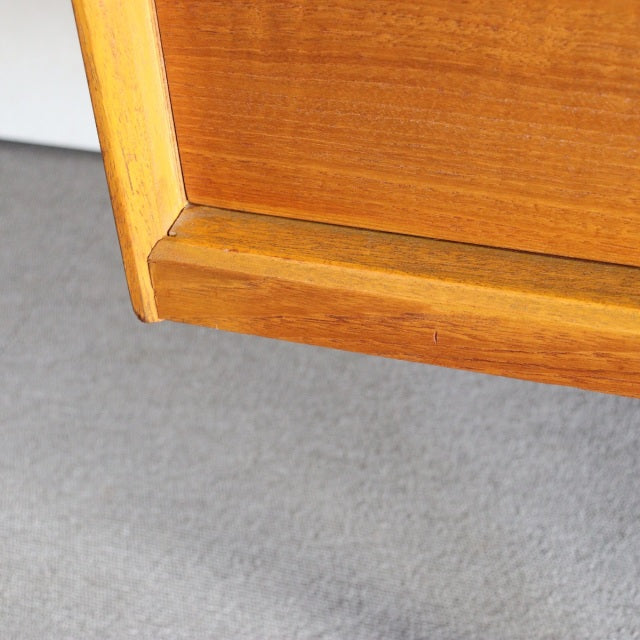 Close-up of vintage teak sideboard corner showing smooth wood grain and mid-century British-Denmark craftsmanship details.