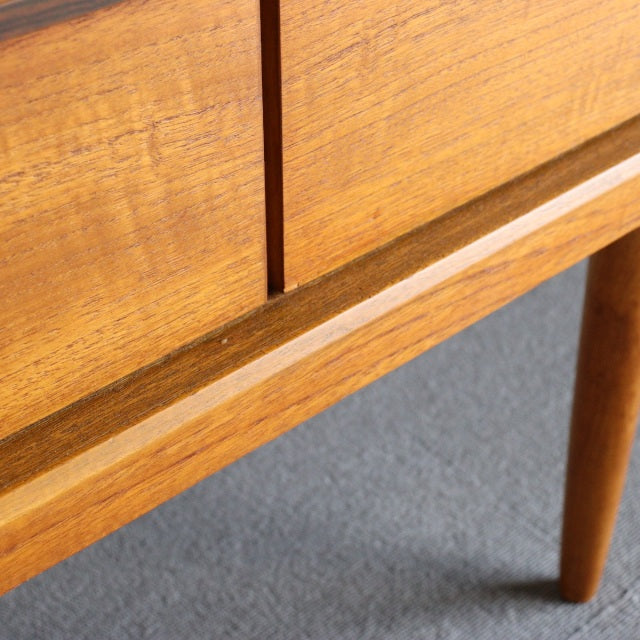 Close-up of vintage teak sideboard leg and lower frame, showcasing smooth wood grain and mid-century British design details.