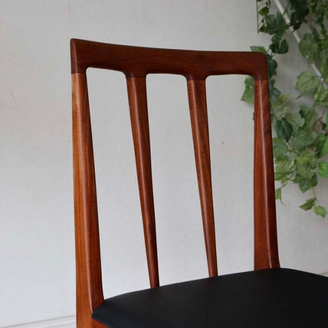 Mid-century British vintage dining chair in teak with vertical slat backrest and black cushioned seat, sleek tapered legs.
