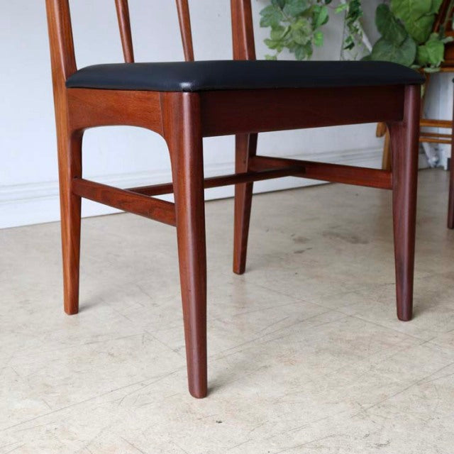 Vintage teak dining chair with British mid-century design, slender tapered legs, and black upholstered seat, crafted in.