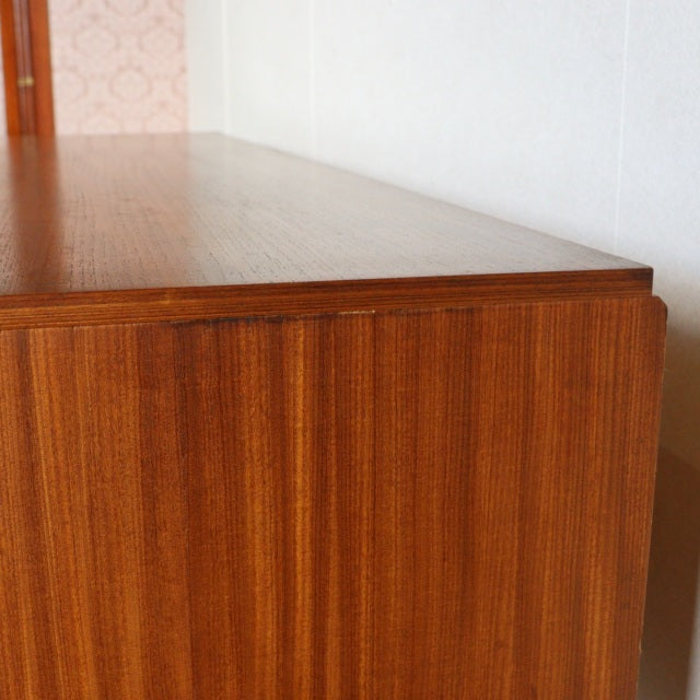 Mid-century British vintage teak sideboard by Austinsuite with smooth wood grain and clean edges against a white wall.