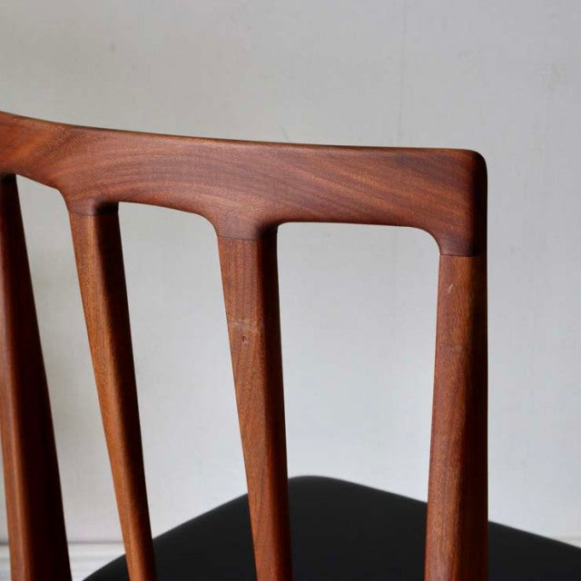 Mid-century British vintage teak dining chair backrest with smooth wood grain and tapered vertical supports.